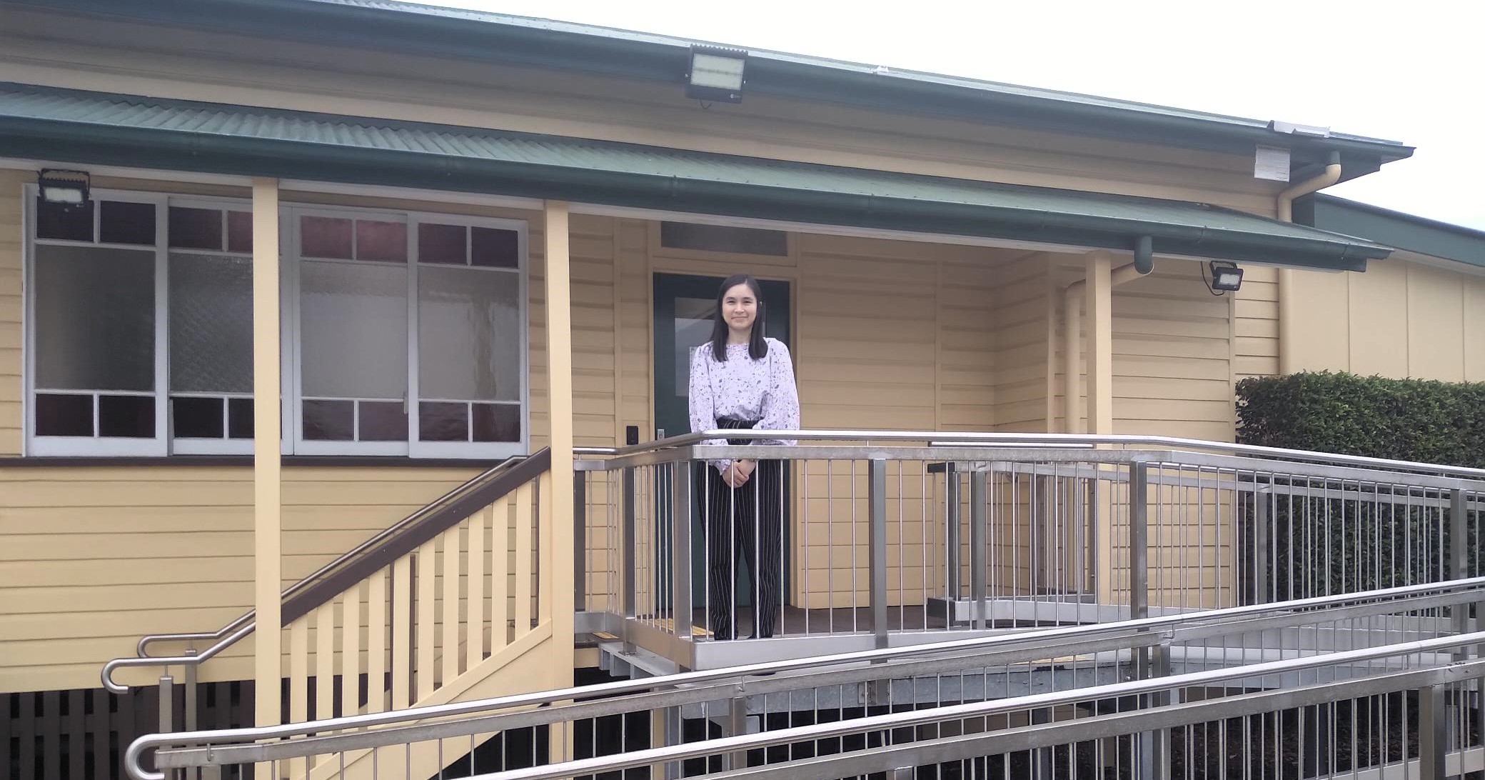 A woman standing in front of a building smiling at the camera